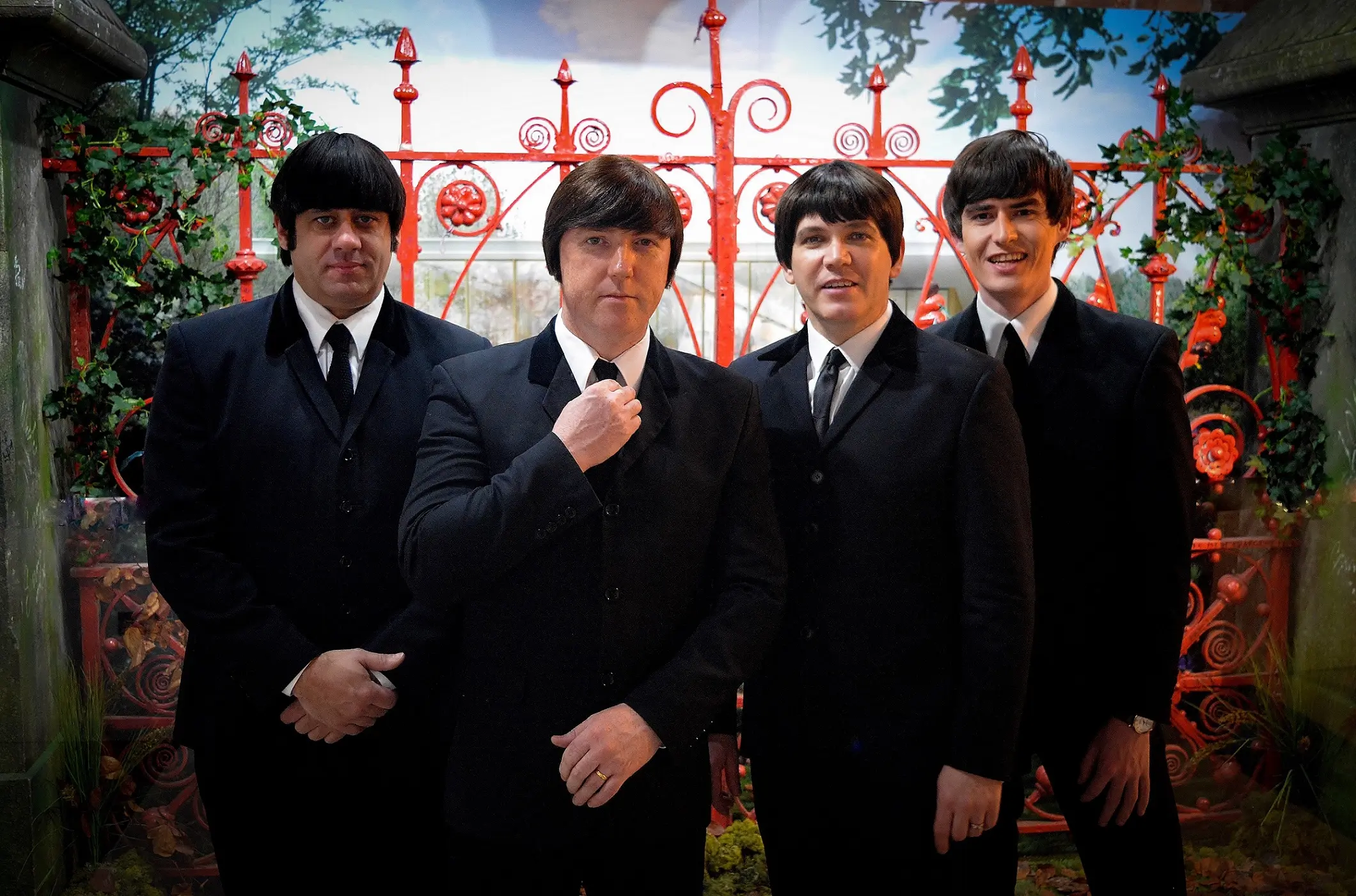 The Mersey Beatles standing in front of the Strawberry Field gates